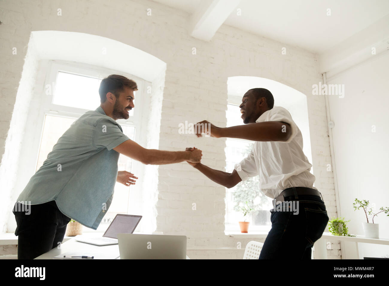 Ufficio eccitato handshaking di lavoratori per celebrare il successo del business Foto Stock