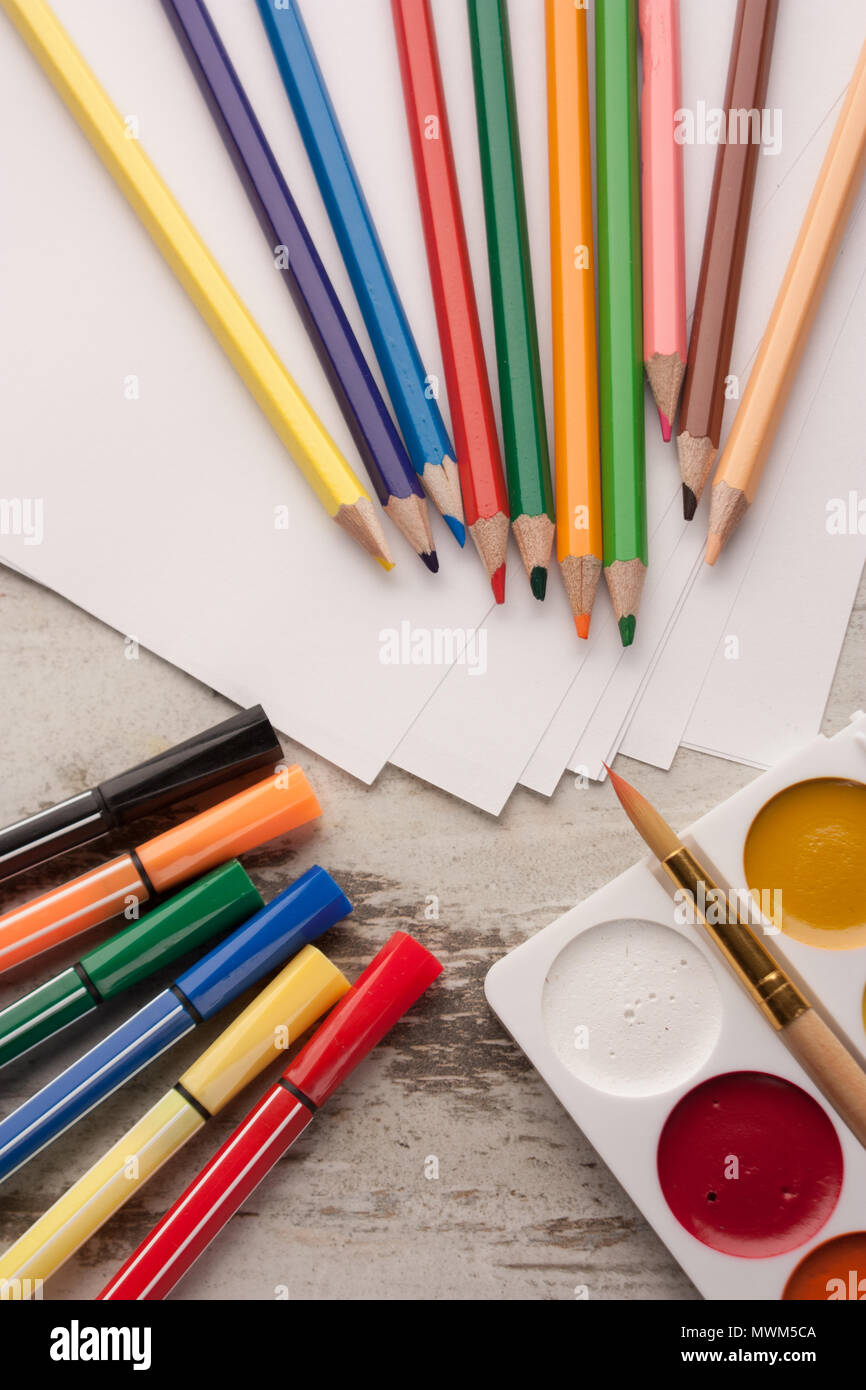 Matite colorate su carta con pennarelli, acquarello e spazzola accanto a.  Un tavolo di legno. Vista dall'alto Foto stock - Alamy
