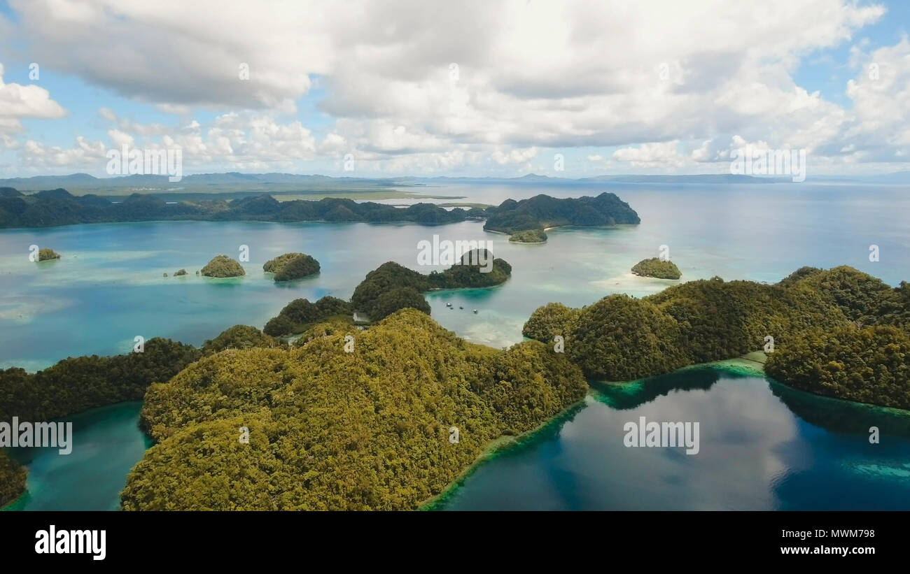 Vista aerea: spiaggia, isola tropicale, Baia Mare e laguna, Siargao. Paesaggio tropicale hill, nuvole e montagne rocce con la foresta pluviale. Acque azzurre della laguna. Paesaggio Shore Bay. Concetto di viaggio. Foto Stock