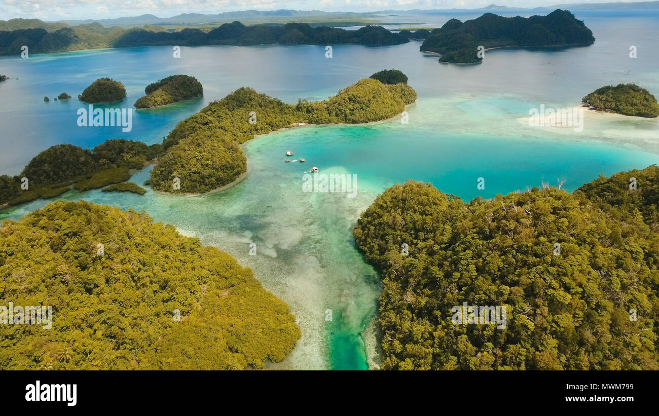 Vista aerea: spiaggia, isola tropicale, Baia Mare e laguna, Siargao. Paesaggio tropicale hill, nuvole e montagne rocce con la foresta pluviale. Acque azzurre della laguna. Paesaggio Shore Bay. Concetto di viaggio. Foto Stock
