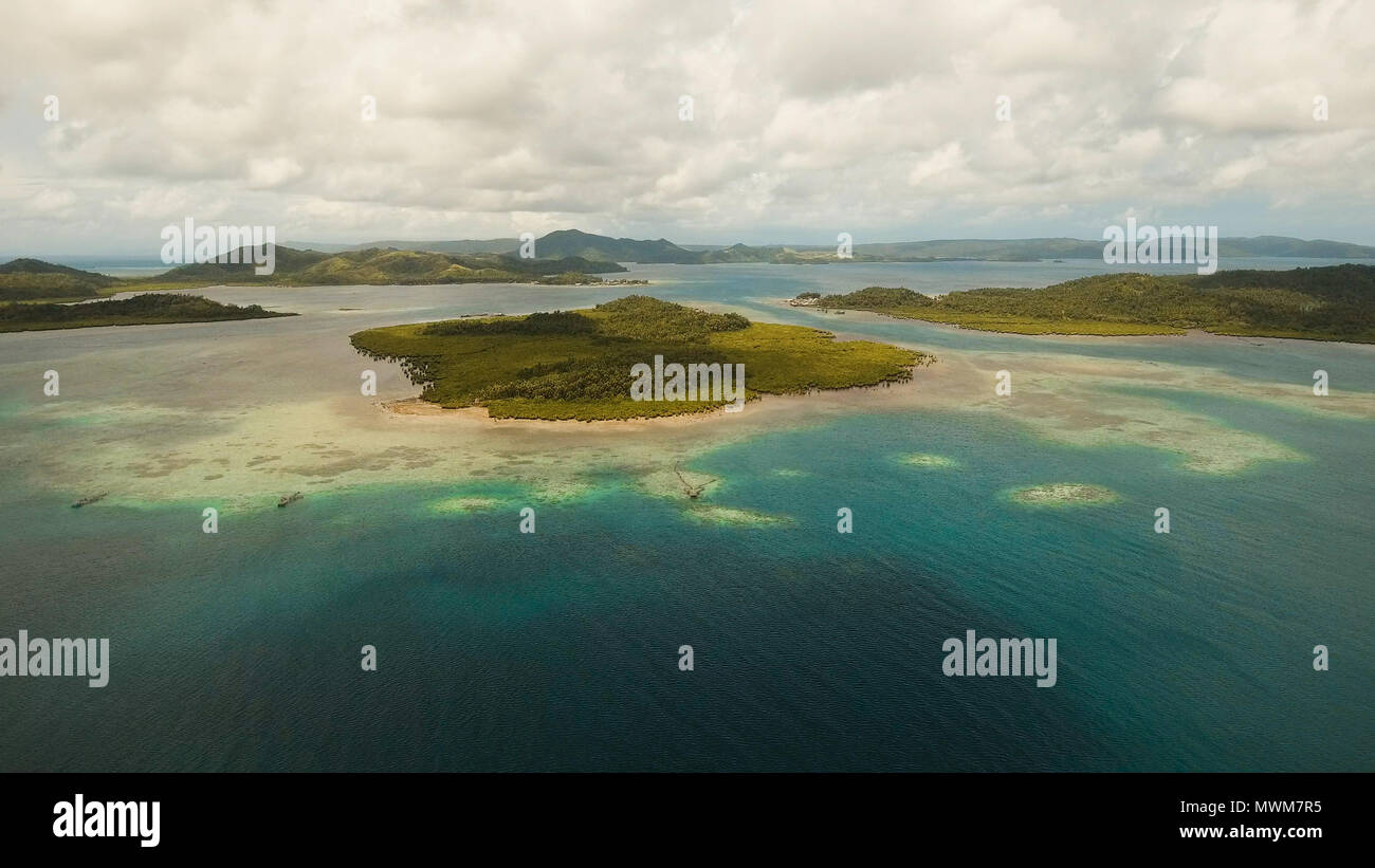 Vista aerea: spiaggia, isola tropicale, Baia Mare e laguna, Siargao. Paesaggio tropicale hill, nuvole e montagne rocce con la foresta pluviale. Acque azzurre della laguna. Paesaggio Shore Bay. Seascape. Concetto di viaggio. Foto Stock
