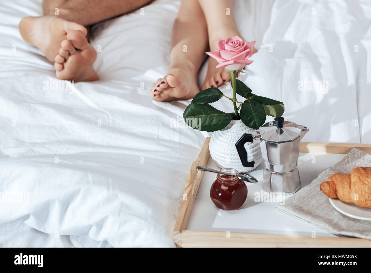 Colazione romantica con croissant e rose sul vassoio nel letto e amare  giovane sullo sfondo Foto stock - Alamy