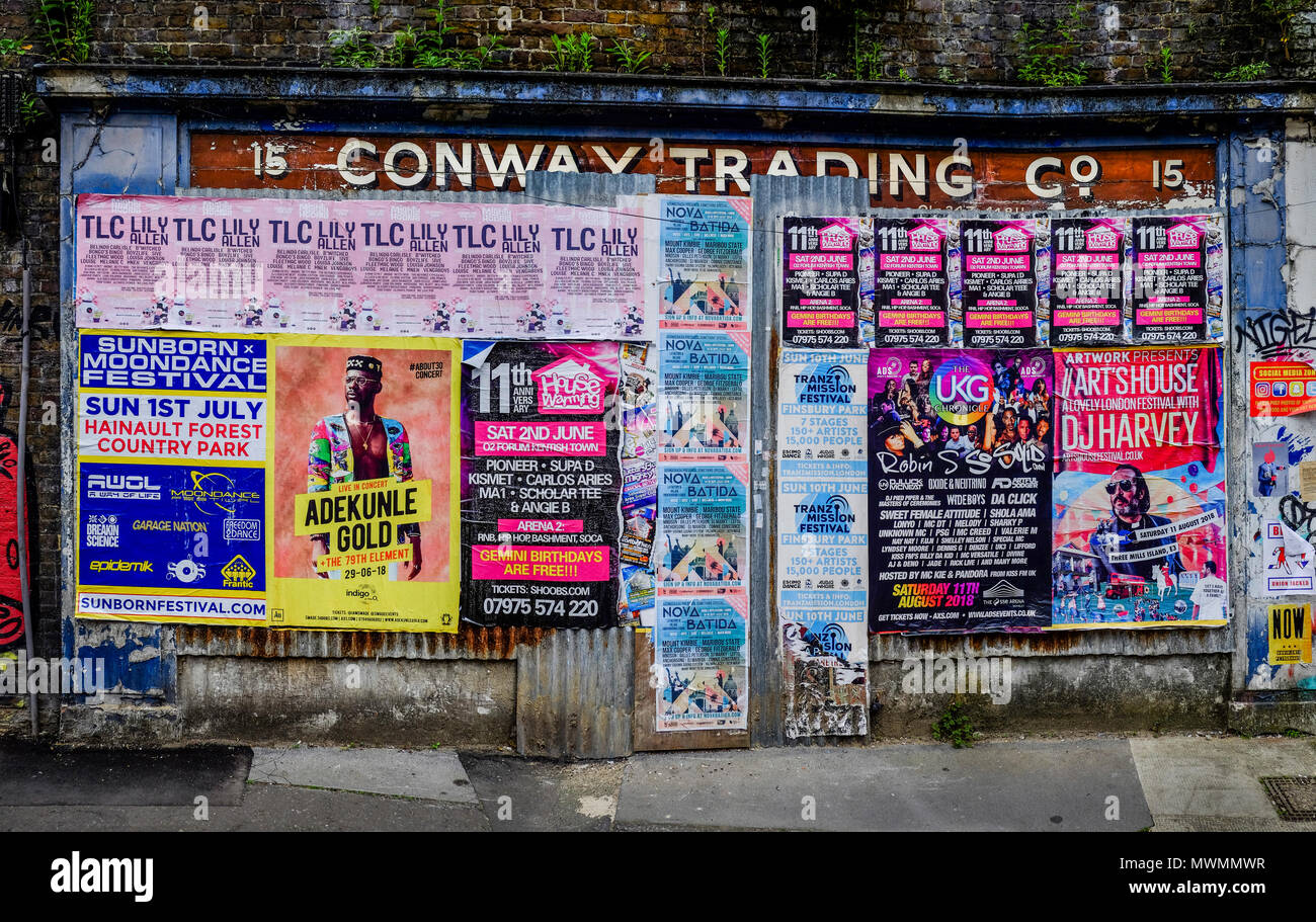 Fly poster a copertura della facciata del negozio abbandonati in east London street, Regno Unito Foto Stock