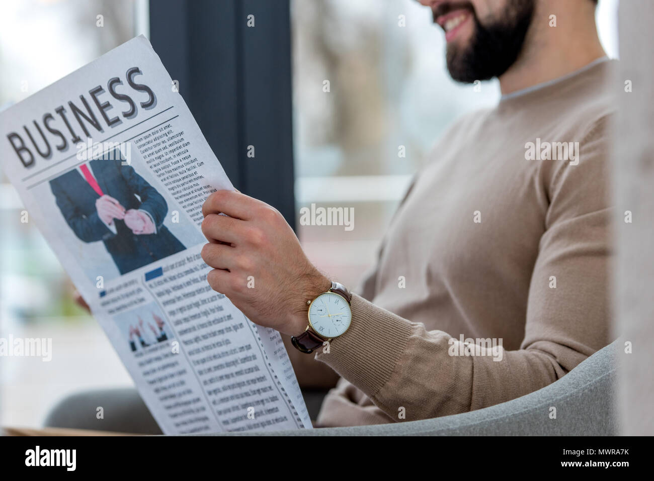 Immagine ritagliata di imprenditore sorridente in seduta cafe e il giornale di lettura Foto Stock