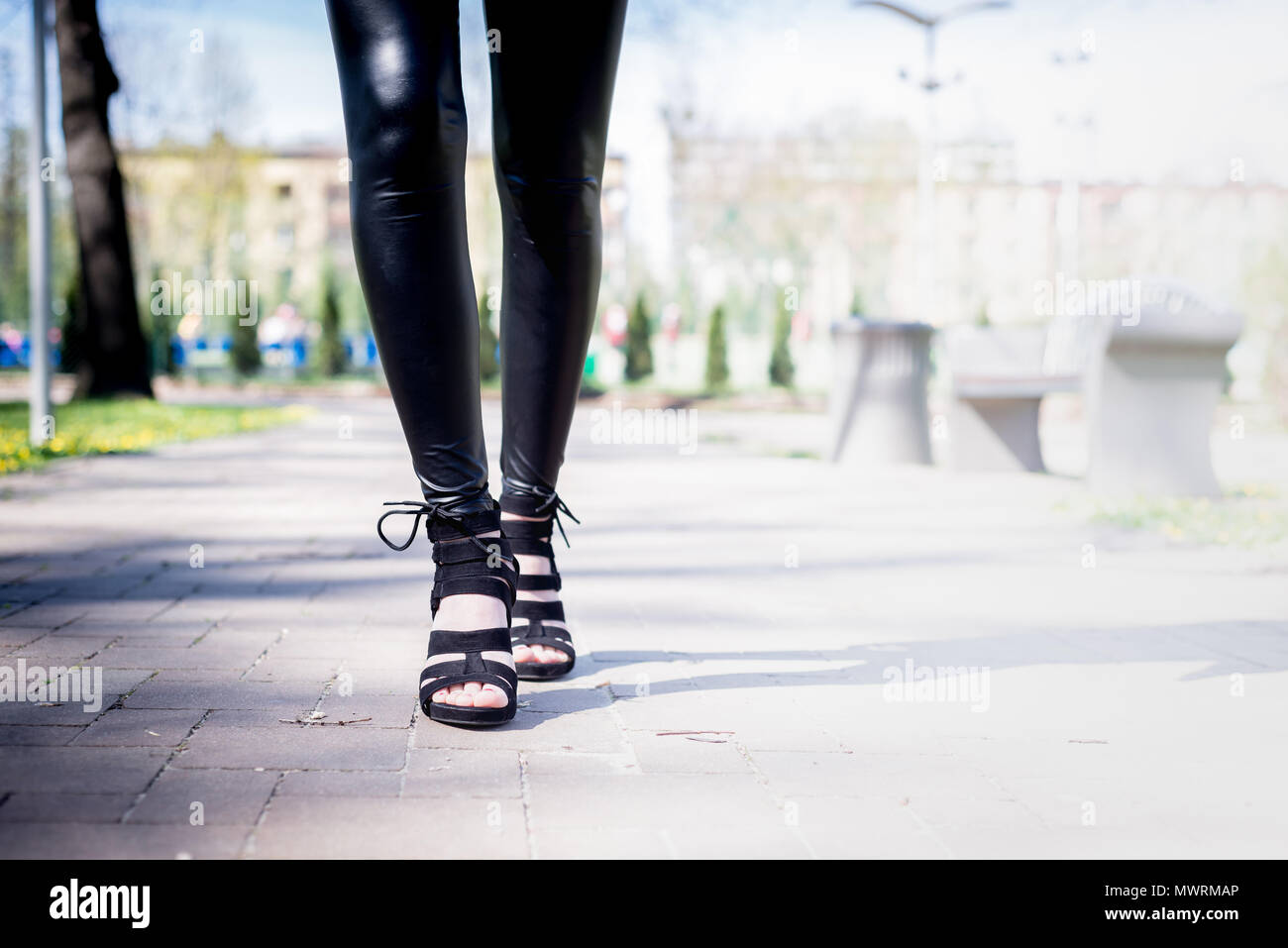 Vista delle gambe di una donna a piedi. Donna indossare tacchi alti scarpe. La ragazza in pantaloni neri si muove intorno al di fuori del parco. Beuty e concetto di moda. Foto Stock
