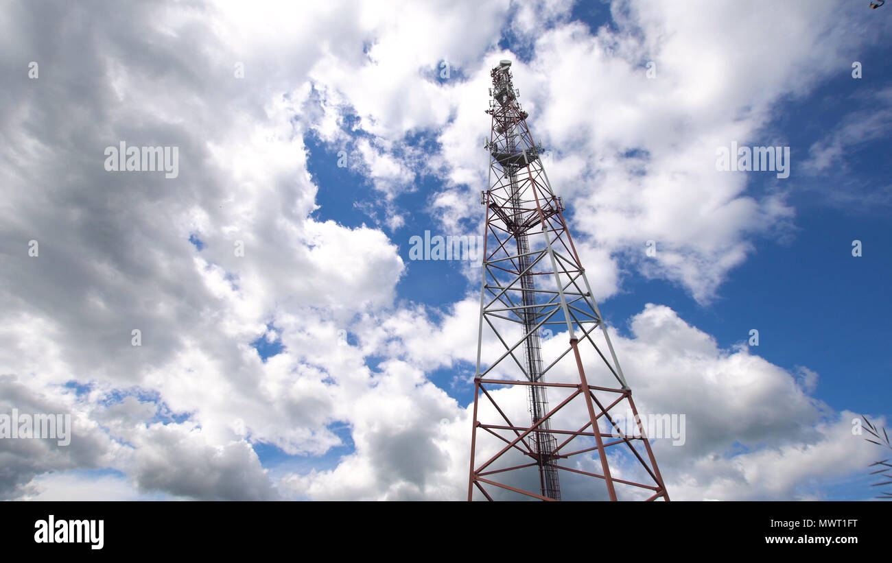 Telefono cellulare la torre contro un cielo blu. Torre di comunicazioni con un sacco di diverse antenne sotto il cielo blu e nuvole. Torre di telecomunicazione con l'azzurro del cielo. Foto Stock