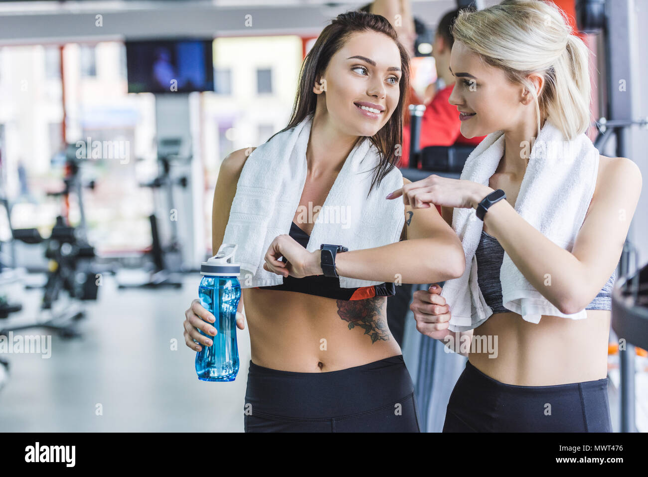 Donne sportive con asciugamani controllo risultati fitnes con smart guarda dopo la formazione presso la palestra Foto Stock