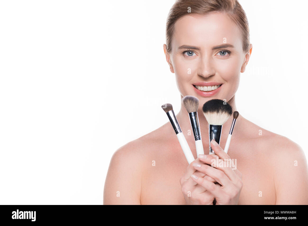 Femmina con la pelle pulita azienda spazzole cosmetiche isolato su bianco Foto Stock