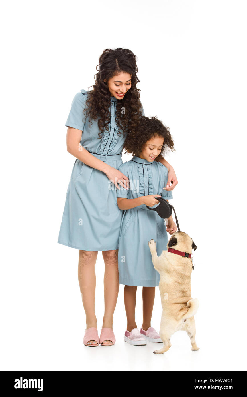 Madre e figlia giocando con il pug cucciolo isolato su bianco Foto Stock