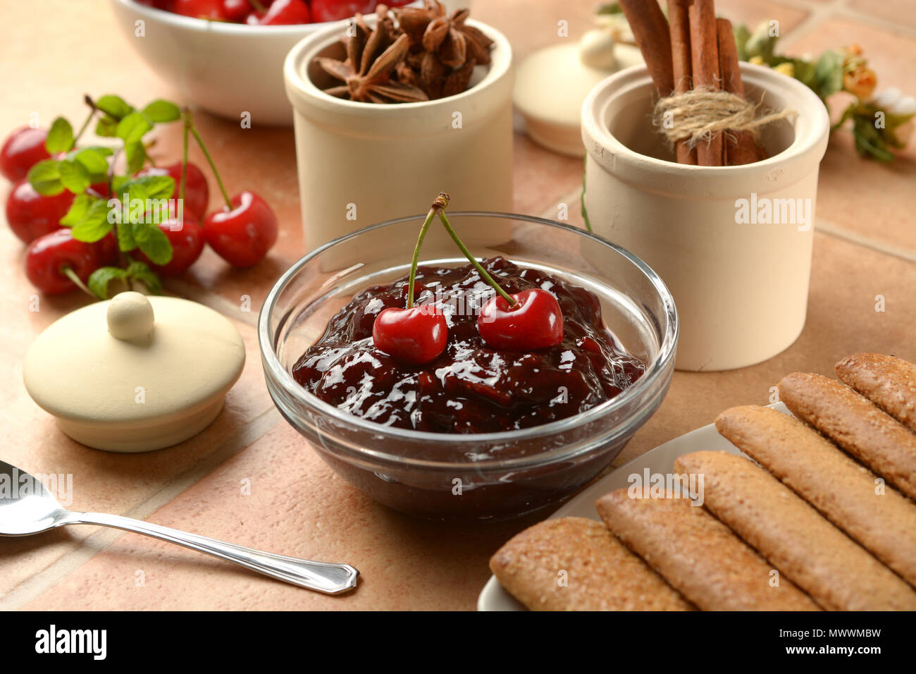 Confettura di ciliegie nella ciotola di vetro con frutti intorno - primo piano Foto Stock
