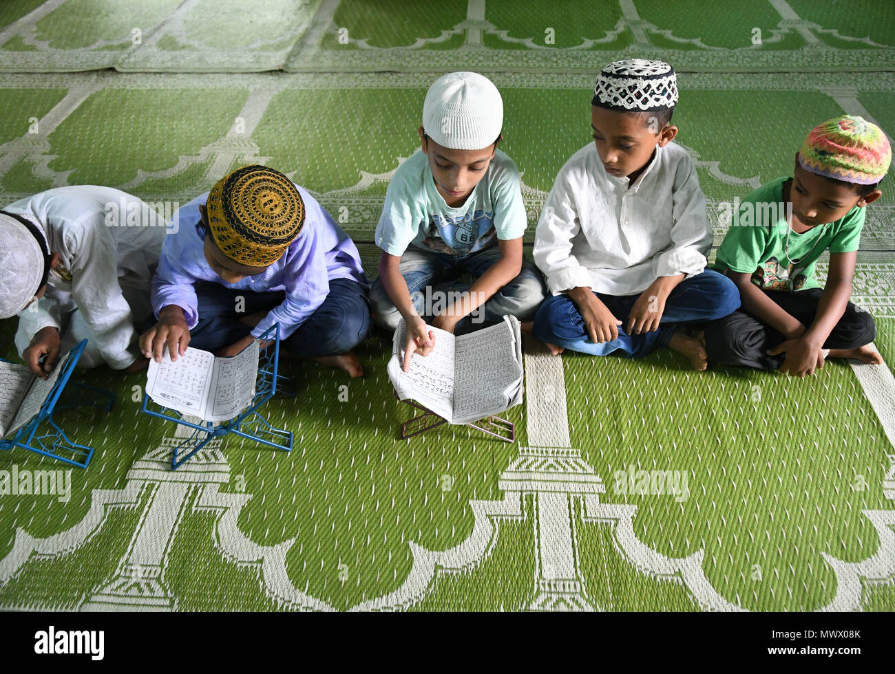 Giovani Musulmani ragazzi visto la lettura del Corano insieme. I bambini si sono riuniti in una madrassa (o una scuola religiosa), durante il sacro mese di digiuno del Ramadan, nella periferia di Agartala. Foto Stock