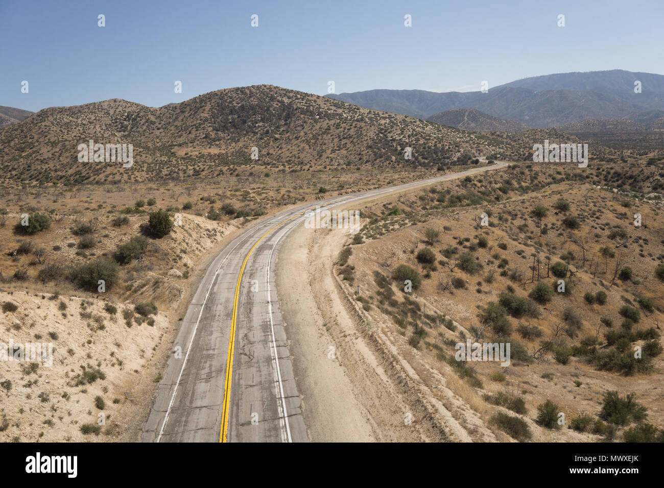 Piegare in un vecchio abbandonato strade del deserto nel deserto del Mojave Desert della California. Foto Stock