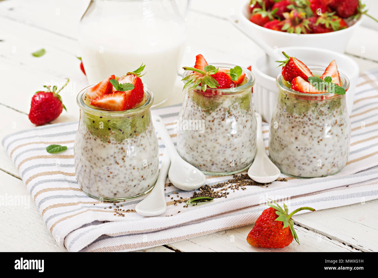 Detox e sana colazione superfoods in barattolo. Vegano latte di cocco semi di chia pudding con fragole e kiwi. Foto Stock