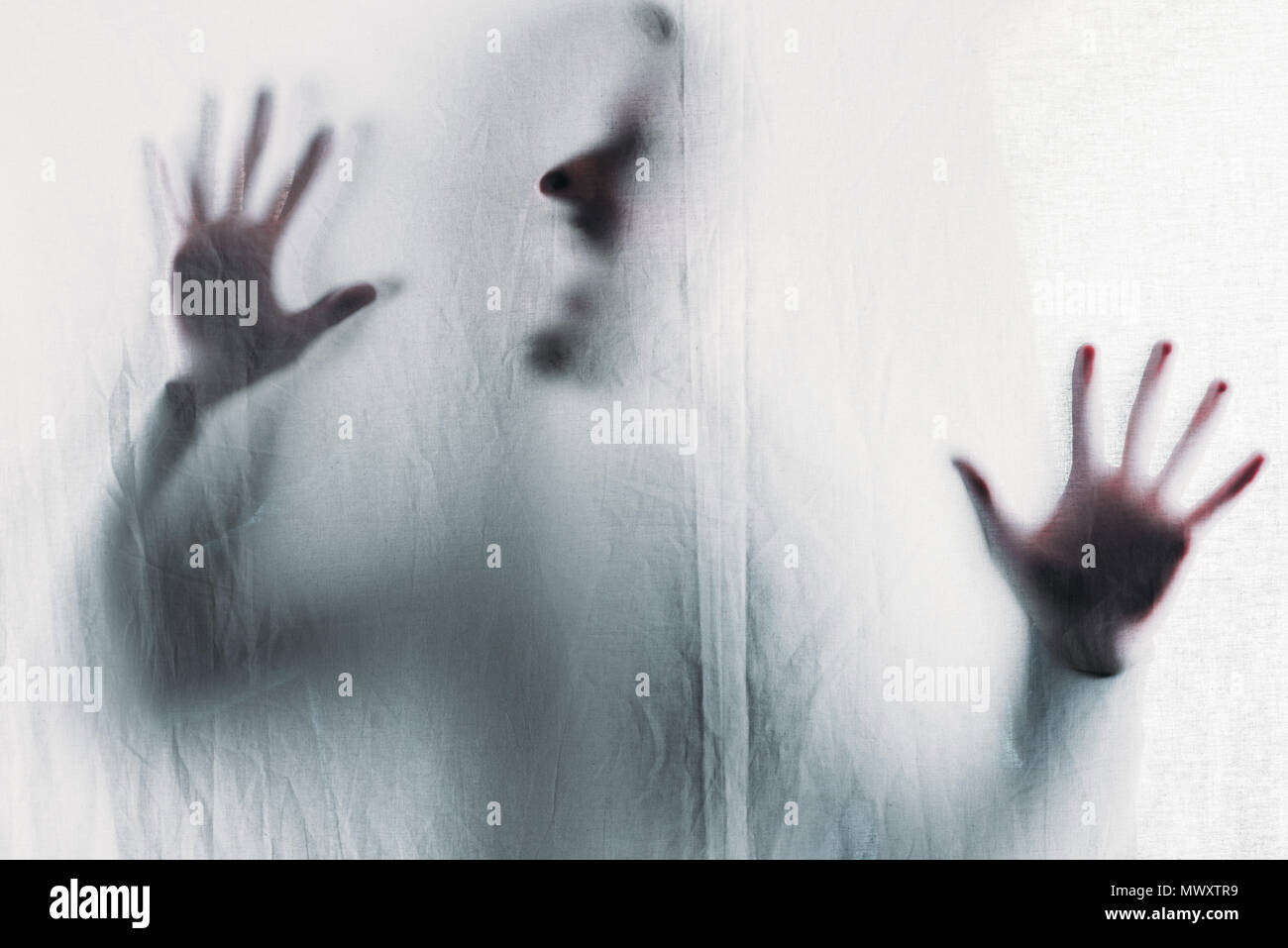Scary sfocata silhouette di un irriconoscibile persona urlando dietro il velo Foto Stock