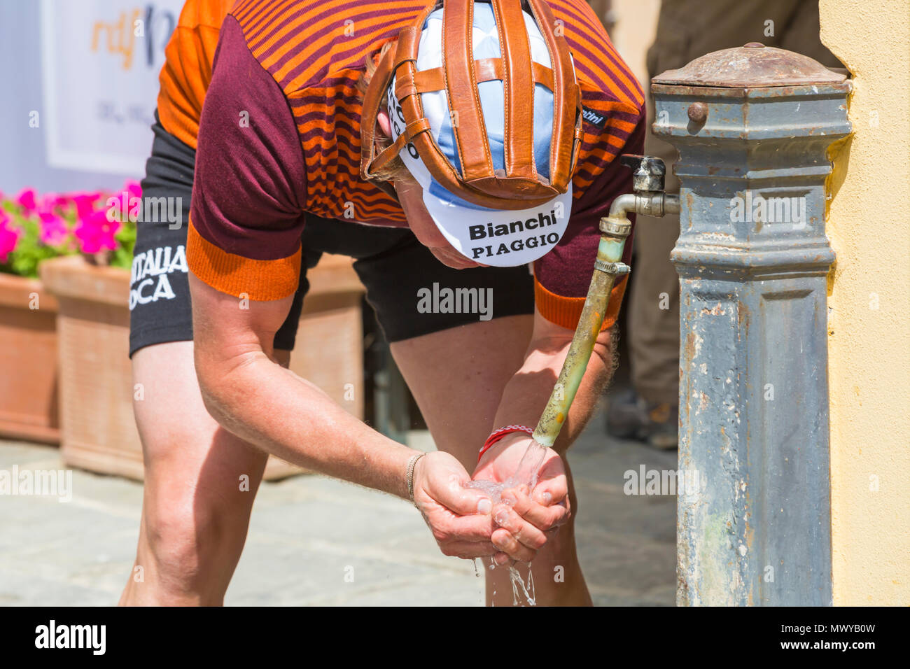 Sosta di ristoro a Montisi per i ciclisti che partecipano all'Eroica Montalcino, Siena, Toscana, Italia a maggio - ciclista con acqua dal rubinetto Foto Stock