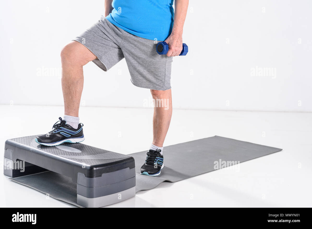 Vista parziale di senior uomo con manubri esercizio sullo stepper isolato su grigio Foto Stock