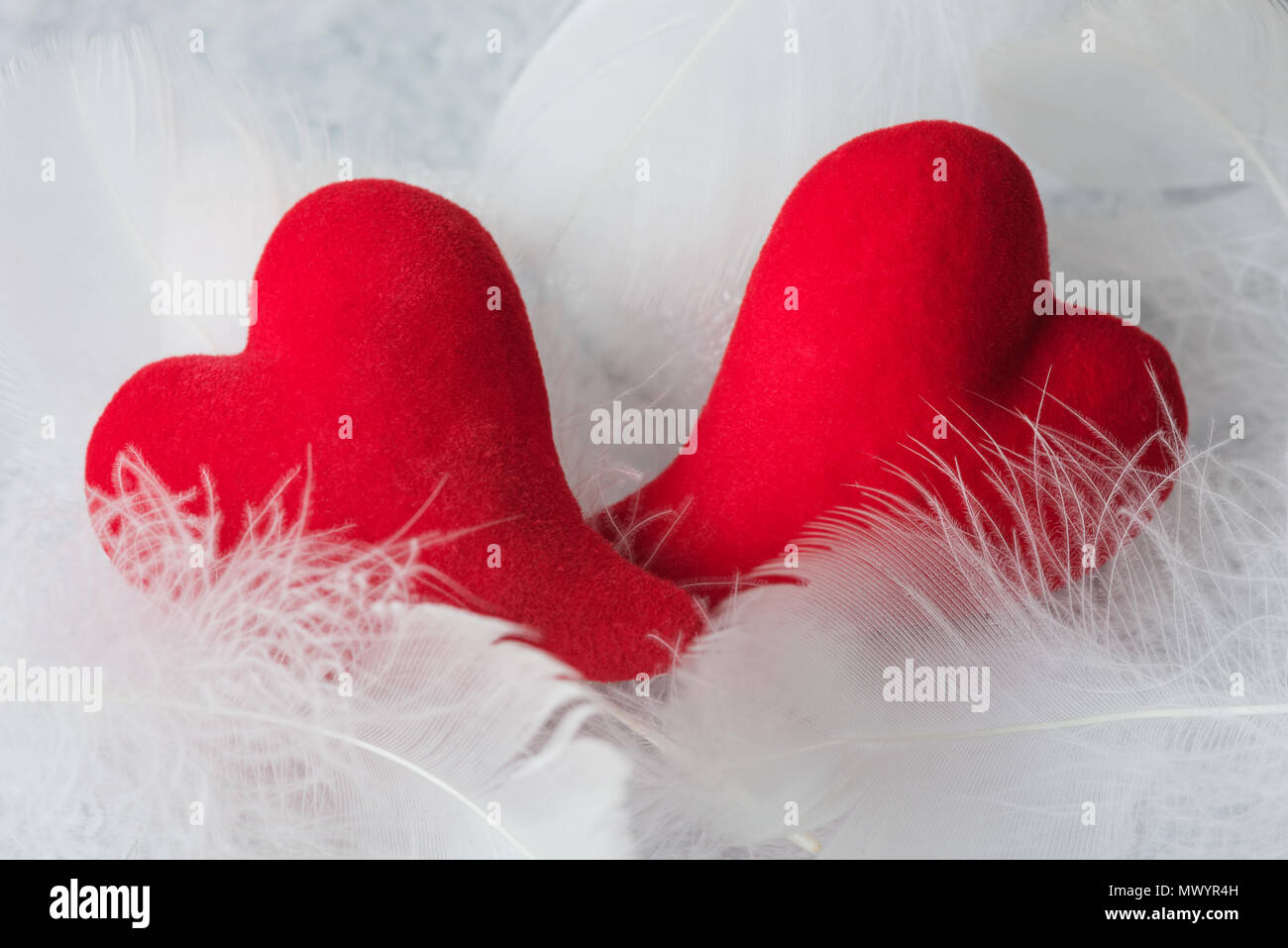 Due cuori rossi giacciono su fluff bianco. Metafora dell'amore. Biglietto di auguri per San Valentino sfondo minerale Foto Stock
