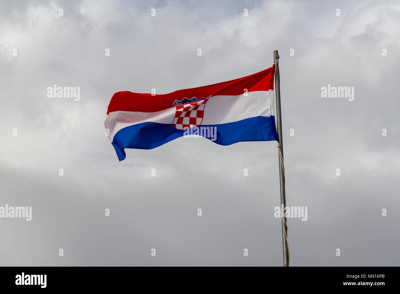 La bandiera croata battenti contro un cielo coperto, sfondo nuvoloso sopra la città vecchia di Dubrovnik, Croazia. Foto Stock