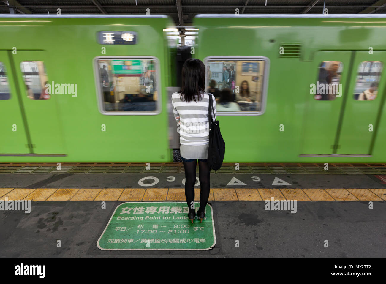 Donna Giapponese in piedi sulla piattaforma di una stazione ferroviaria in una donna-solo l'area di imbarco a Tokyo in Giappone Foto Stock