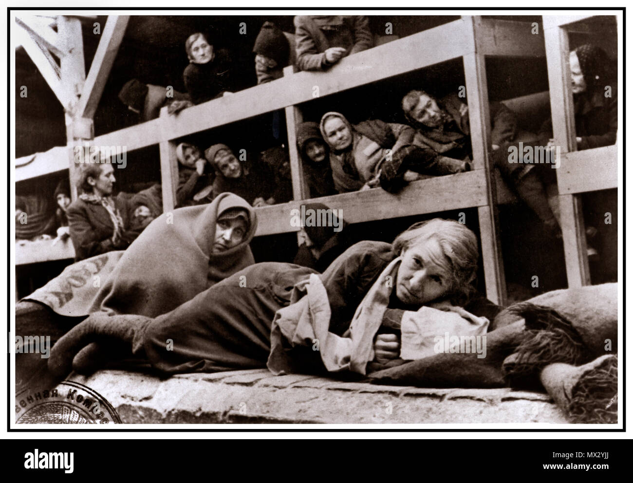 1940's olocausto WW2 Auschwitz - Birkenau Germania nazista del campo di concentramento. Blocco di cella interno con donne prigionieri incarcerati imprigionato detenute nel congelamento cramped degradare le disumane condizioni di questo stark grim emotionless scena ha salutato i loro liberatori in 1945. Più di 1.1 milioni di persone sono morte di Auschwitz, compresi quasi un milione di ebrei. Coloro che non sono stati inviati direttamente alle camere a gas sono stati condannati ai lavori forzati. Il campo di Auschwitz era complesso essenziale per eseguire il piano nazista per la "Soluzione Finale". Auschwitz ha lasciato il segno come uno dei più famigerati Campi della II Guerra Mondiale Foto Stock