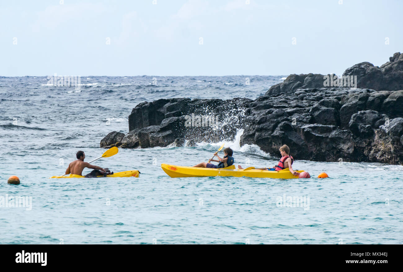 Canoisti paddling vicino a spiaggia rocciosa, con wave rottura, Anakena, Isola di Pasqua, Rapa Nui, Cile Foto Stock