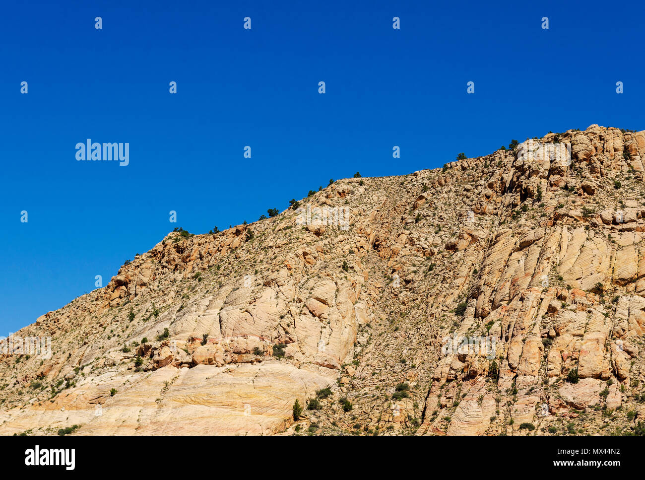 White rock montagne coperte con ripide scogliere sotto il luminoso cielo blu. Foto Stock