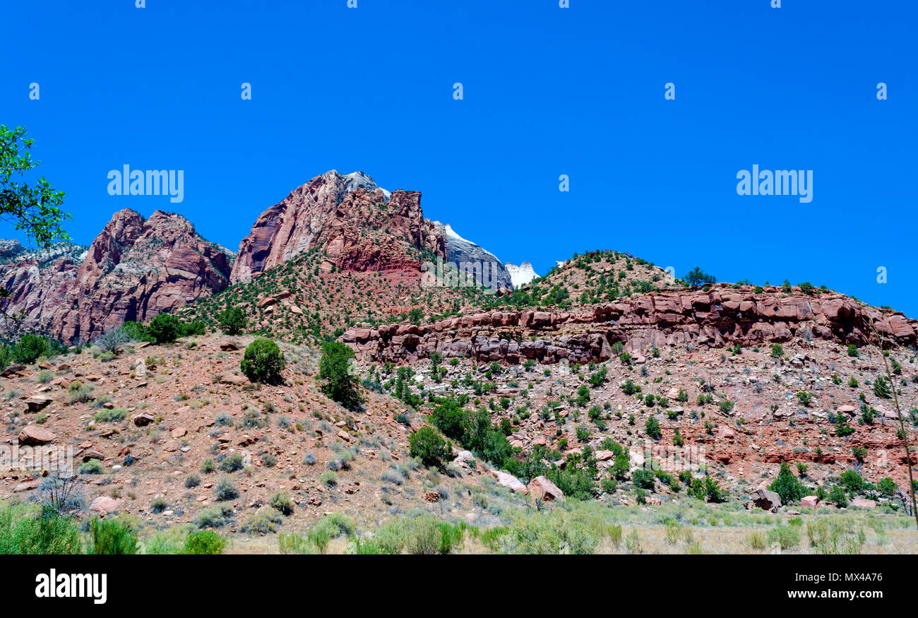 Vista panoramica di tall Red Rock Mountains con alberi e arbusti verdi sotto un luminoso cielo blu. Foto Stock