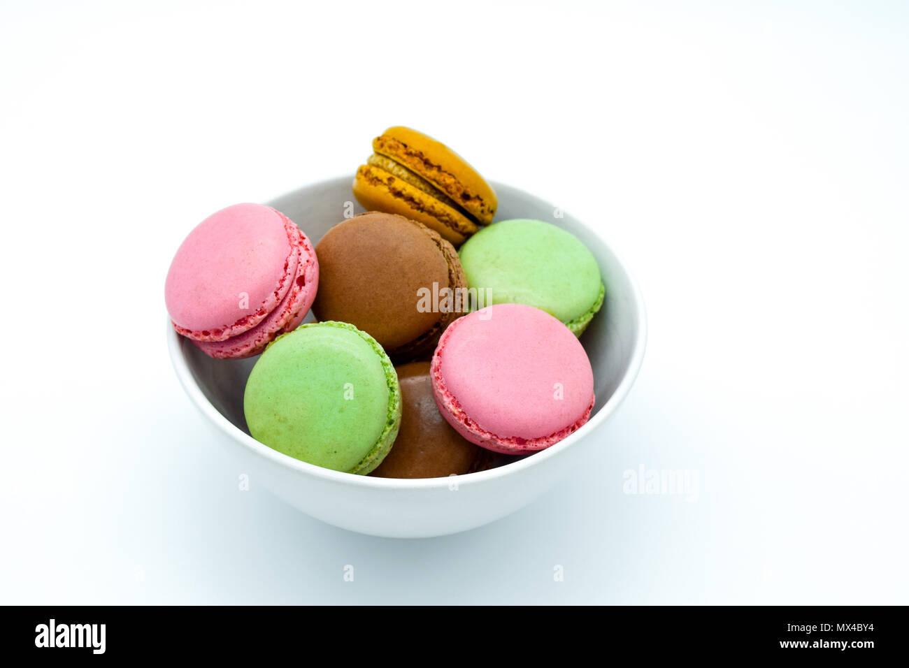 Macarons nella ciotola, dolci macaron colorati su sfondo bianco Foto Stock