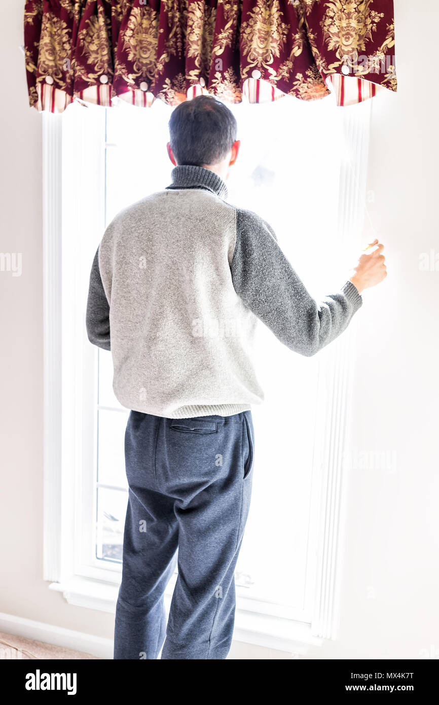 Uomo in piedi nella parte anteriore della finestra luminosa in camera home la regolazione di vecchio stile retrò persiane oscuranti Foto Stock