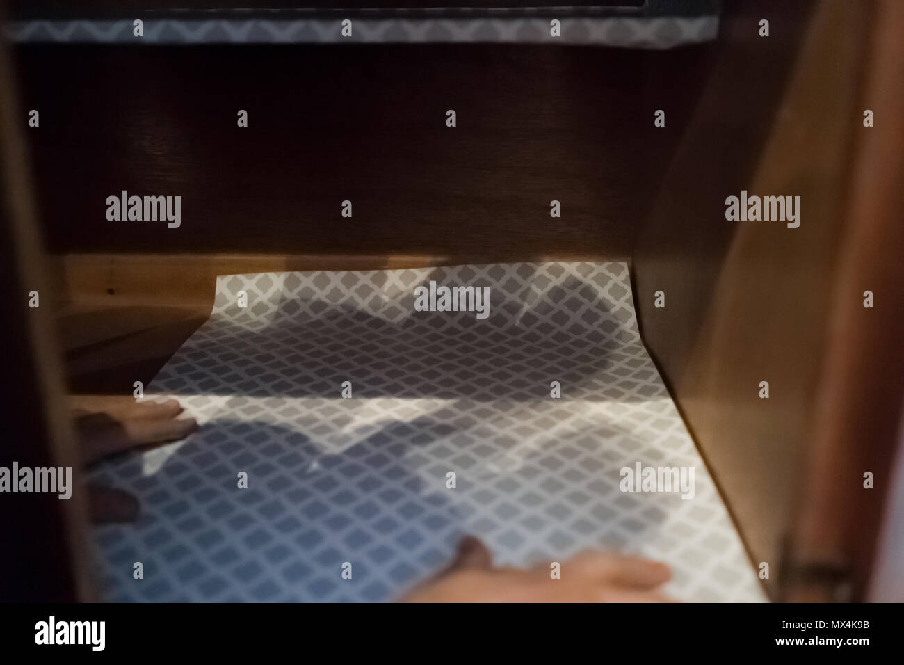 L'uomo immissione camicia di protezione in foglio all'interno su armadi in legno con le mani nei cassetti da cucina Foto Stock