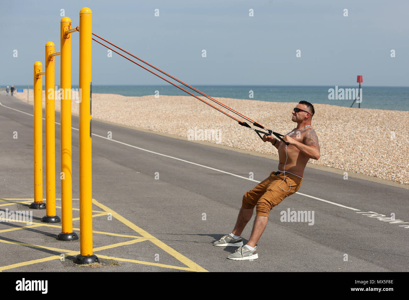Un uomo nella foto utilizzando outdoor attrezzatura ginnica sulla spiaggia a Bognor Regis, West Sussex, Regno Unito. Foto Stock