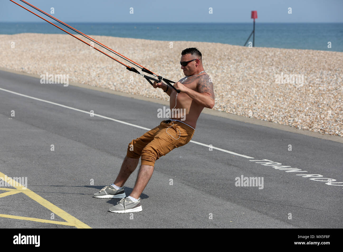 Un uomo nella foto utilizzando outdoor attrezzatura ginnica sulla spiaggia a Bognor Regis, West Sussex, Regno Unito. Foto Stock