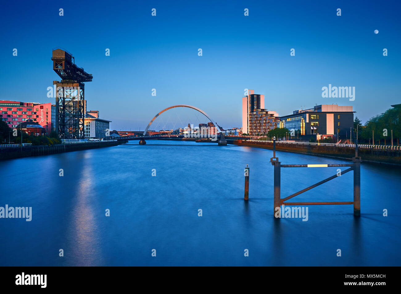 Una lunga esposizione immagine presa dal bicchiere del ponte sul fiume Clyde che mostra i famosi punti di riferimento di Glasgow, il Clyde Arc Bridge e il Finnieston gru Foto Stock