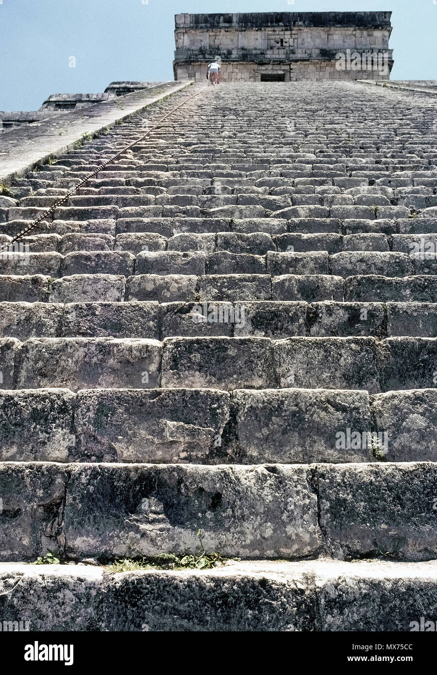 Un basso angolo di vista guardando la maggior parte dei 91 ripidi passaggi di calcare che salgono verso l'alto di El Castillo (Castello), noto anche come tempio di Kukulcan, più famose rovine Maya in antico sito archeologico di Chichen Itza sulla penisola dello Yucatan in Messico. Avvicinandosi al vertice è un turista che sta salendo a 45 gradi scala di questa piramide a gradini tenendo premuto su una lunga catena di metallo per la sicurezza. Fin da quando un alpinista cadde alla sua morte nel 2006, i visitatori non sono più ammessi a salire il 99 piedi di altezza (30 metri di struttura). Il pre-Colombiano landmark è un sito Patrimonio Mondiale dell'UNESCO. Foto Stock