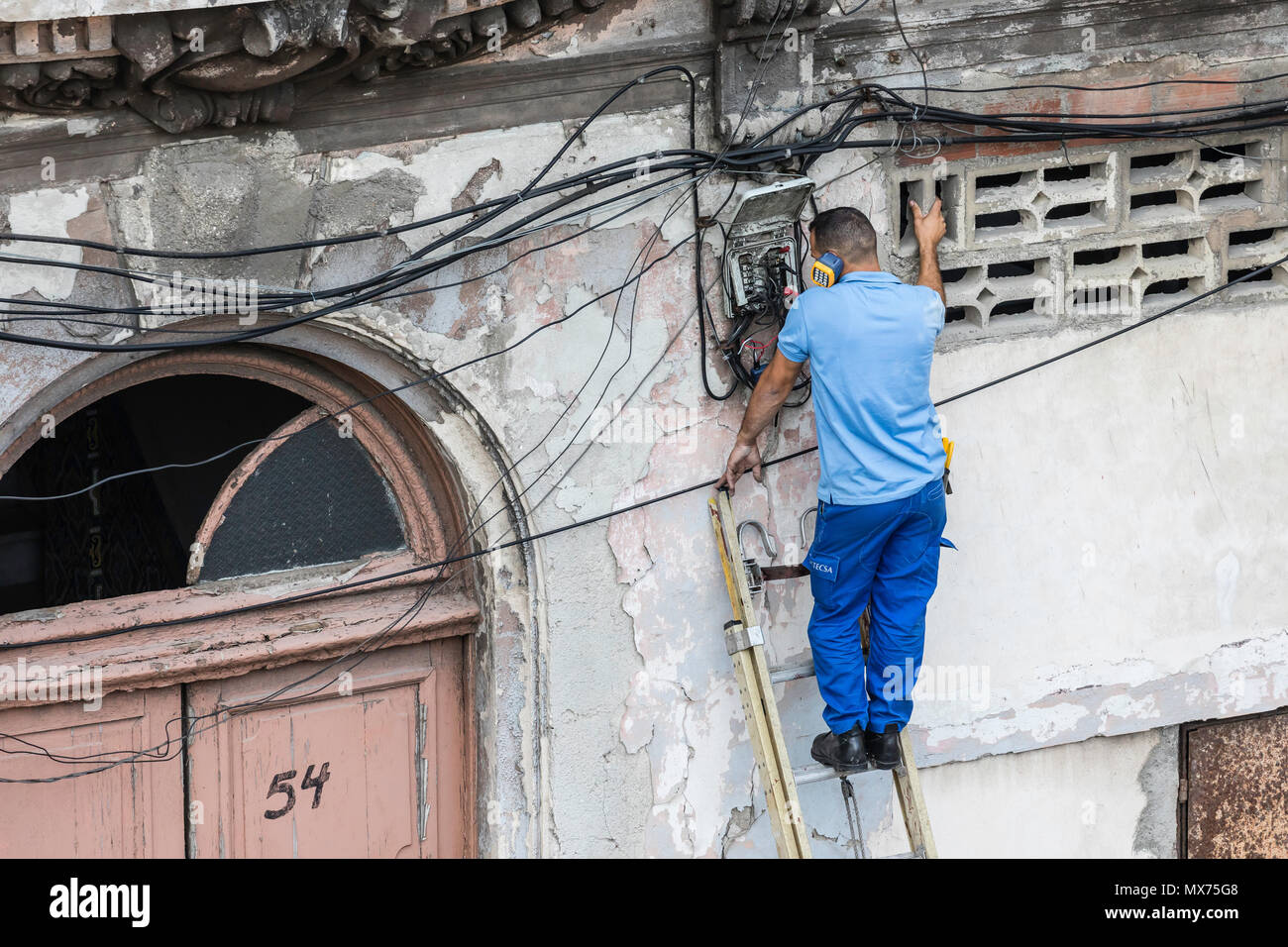 Un lavoratore che fissa le linee telefoniche nella vecchia Havana, Cuba Foto Stock