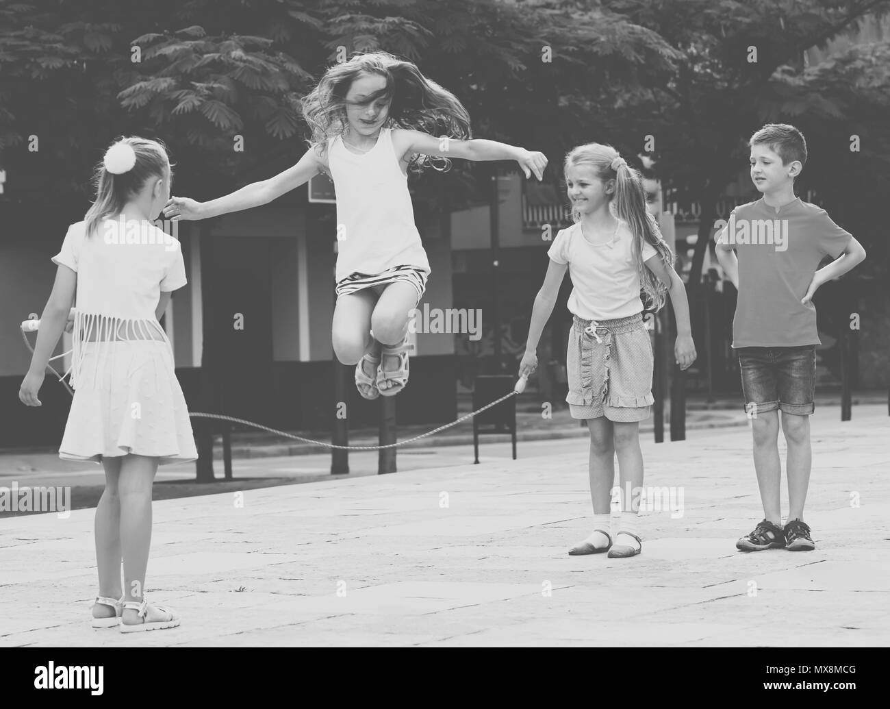 Il gruppo di allegro bambini saltando insieme con il salto con la corda sul  parco giochi urbano Foto stock - Alamy