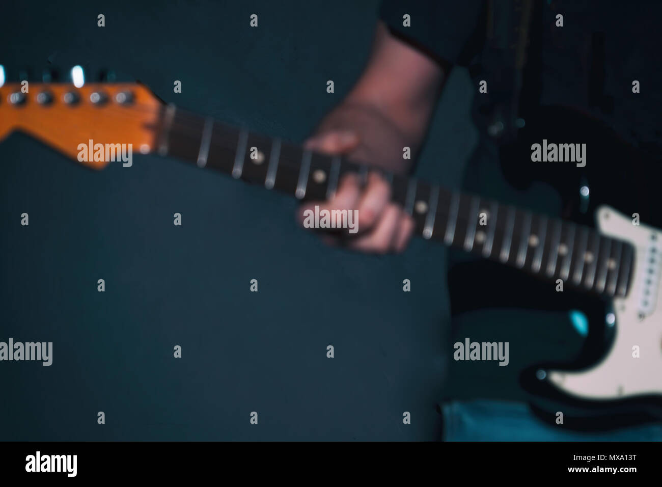 Immagine sfocata. Un lettore gitar con una chitarra in una stanza buia Foto Stock