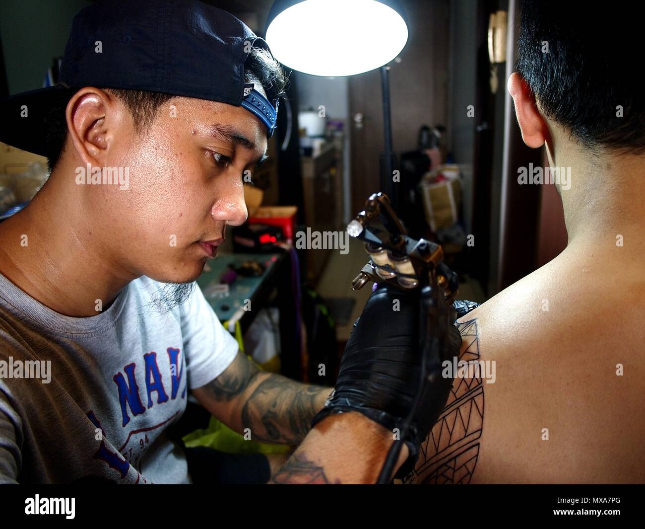 MANDALUYONG City, Filippine - 27 Maggio 2018: Un tatuaggio artista lavora su un tatuaggio sulla spalla di un cliente. Foto Stock