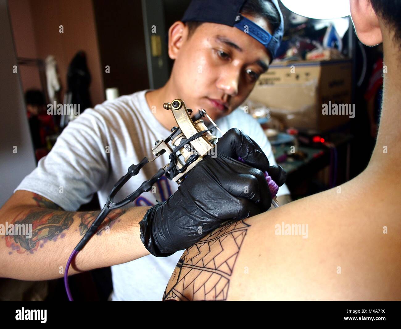 MANDALUYONG City, Filippine - 27 Maggio 2018: Un tatuaggio artista lavora su un tatuaggio sulla spalla di un cliente. Foto Stock