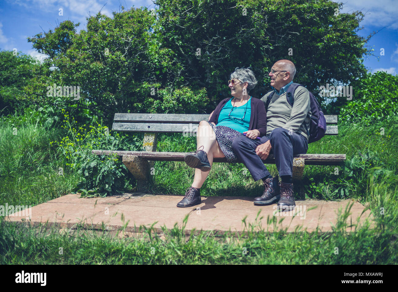 Una coppia senior è rilassante su un banco in natura in un giorno di estate Foto Stock