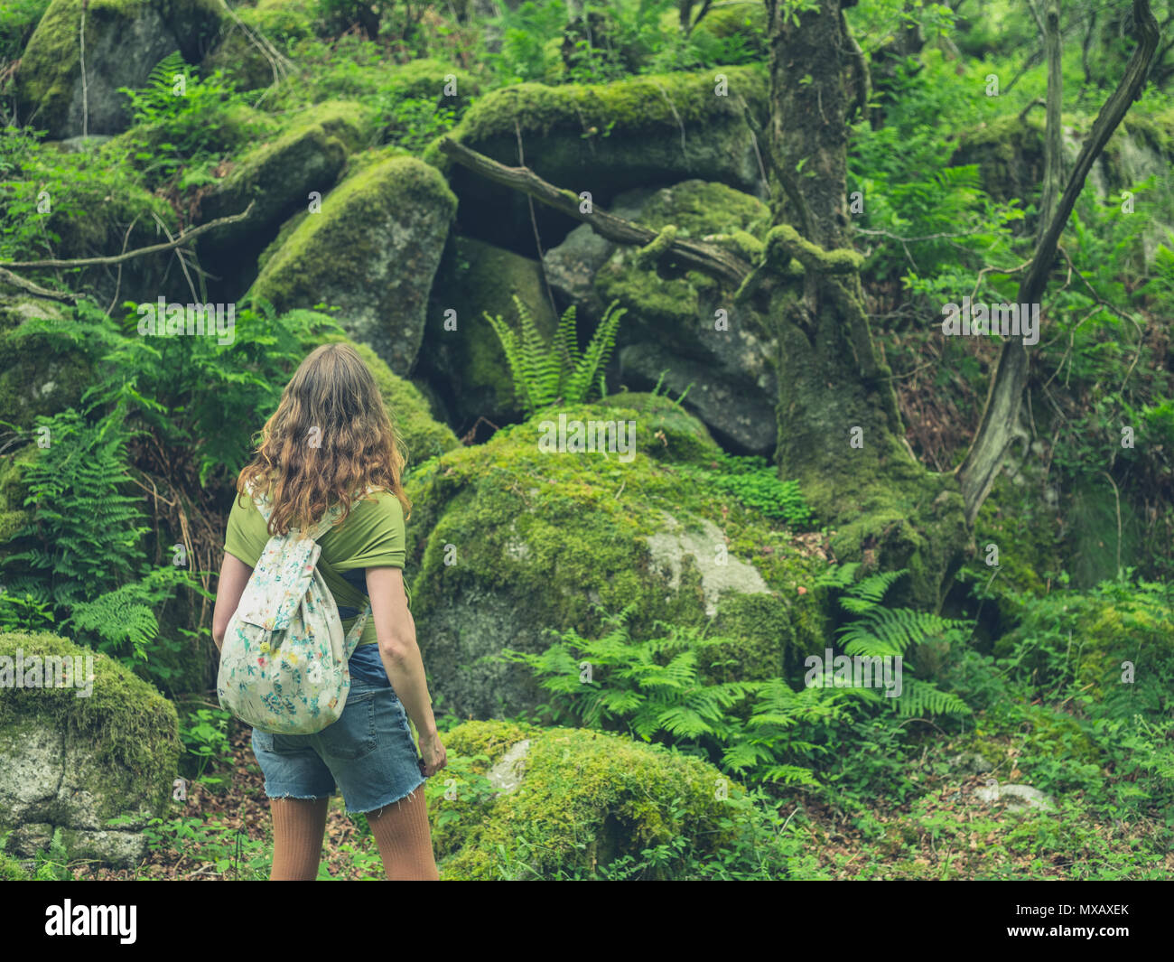 Una giovane donna sta camminando nella foresta Foto Stock