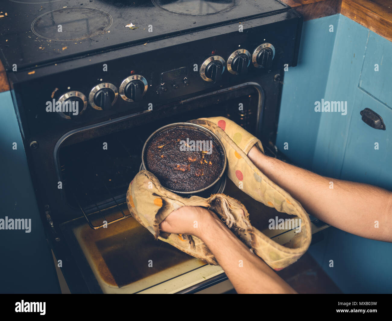 Nelle mani di un uomo è la rimozione di un olocausto torta dal forno Foto Stock