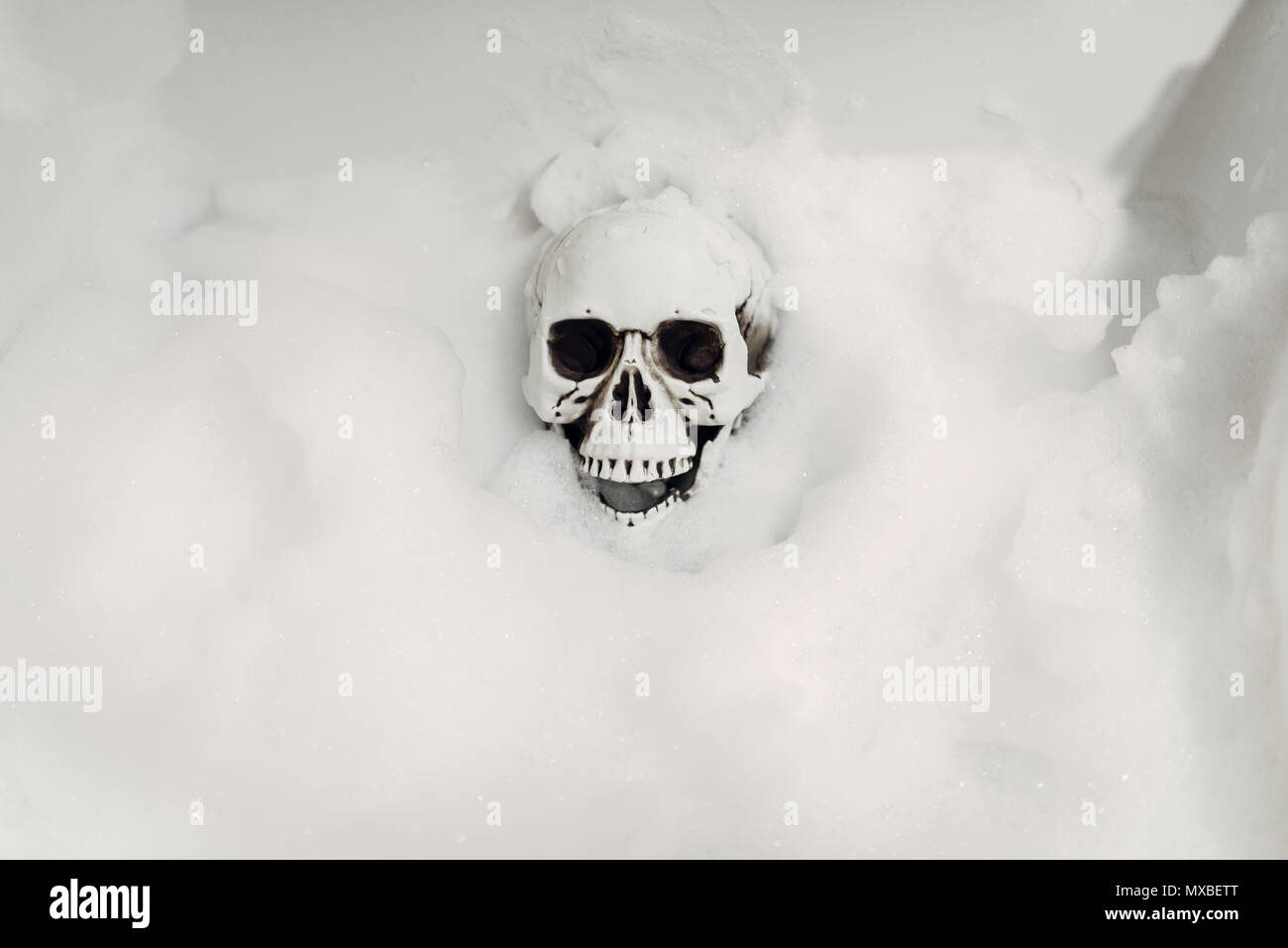 Scary scheletro umano sdraiato nella vasca da bagno in schiuma, umorismo nero, scherzo o sorpresa Foto Stock