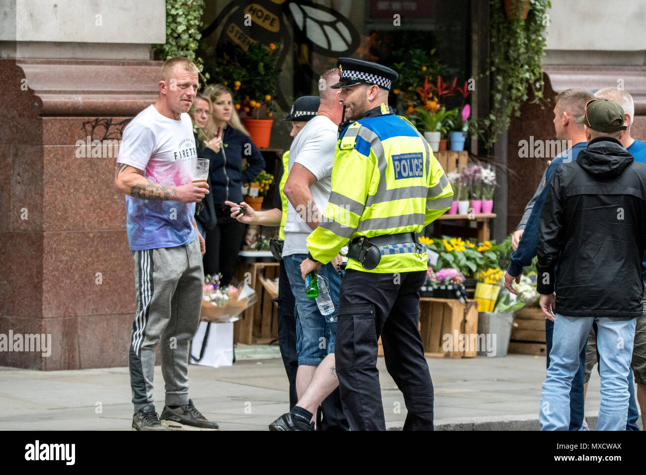 2 Giugno 2018 - Il calcio democratico Lads Alliance (DFLA) e libera Tommy Robinson attivisti marzo e dimostrare attraverso le strade di Manchester. La polizia arresta un maschio da bere per le strade di fronte a un negozio di fiori con un gigante di Manchester Bee murale nella finestra . Foto Stock