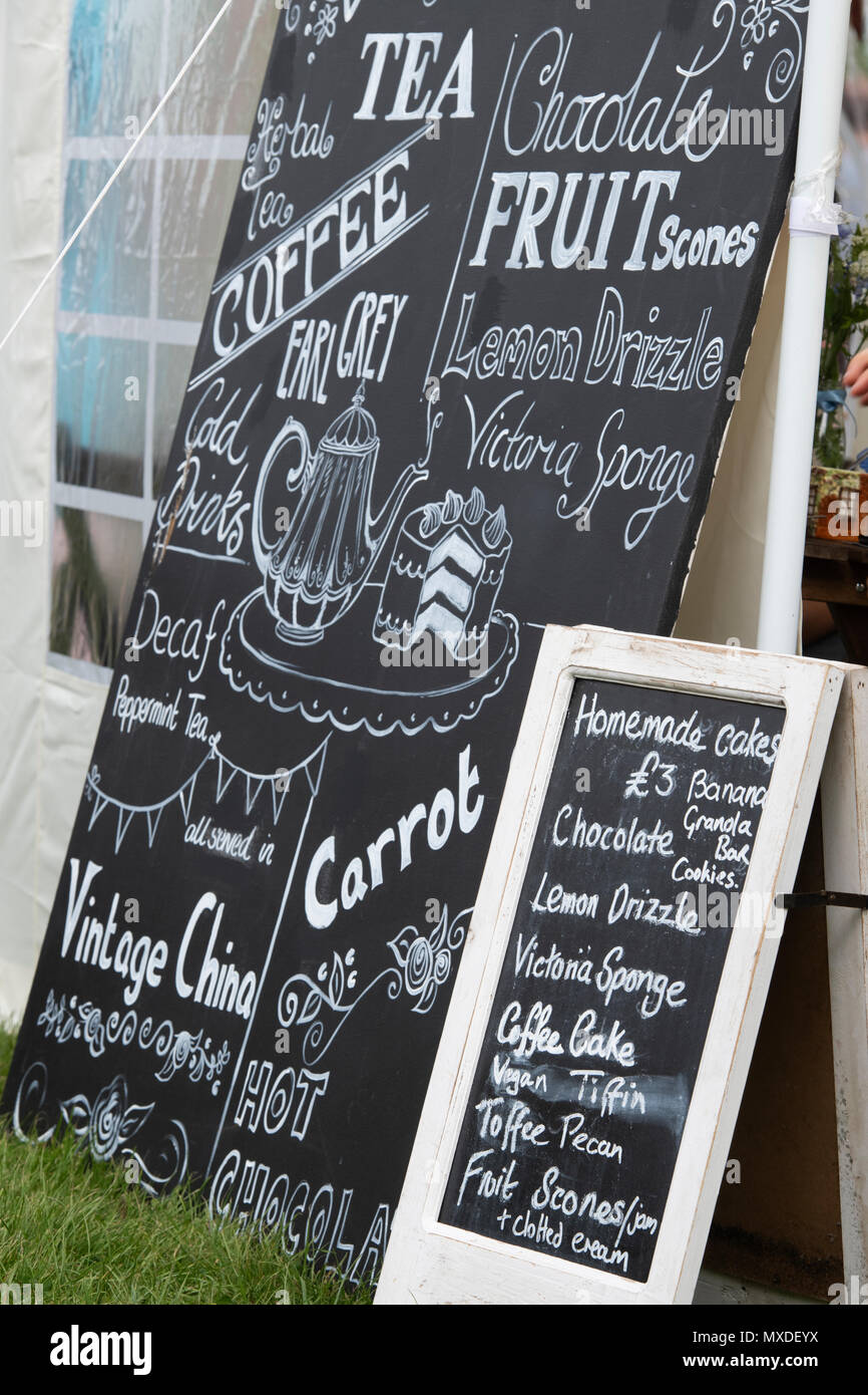 Tè e una fetta di torta marquee chalkboard segno ad un festival di cibo. Oxfordshire, Inghilterra Foto Stock