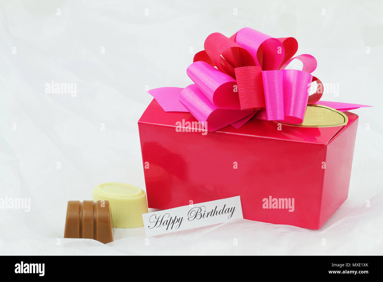Buon compleanno carta rosa con scatola di cioccolatini sul tessile bianco Foto Stock