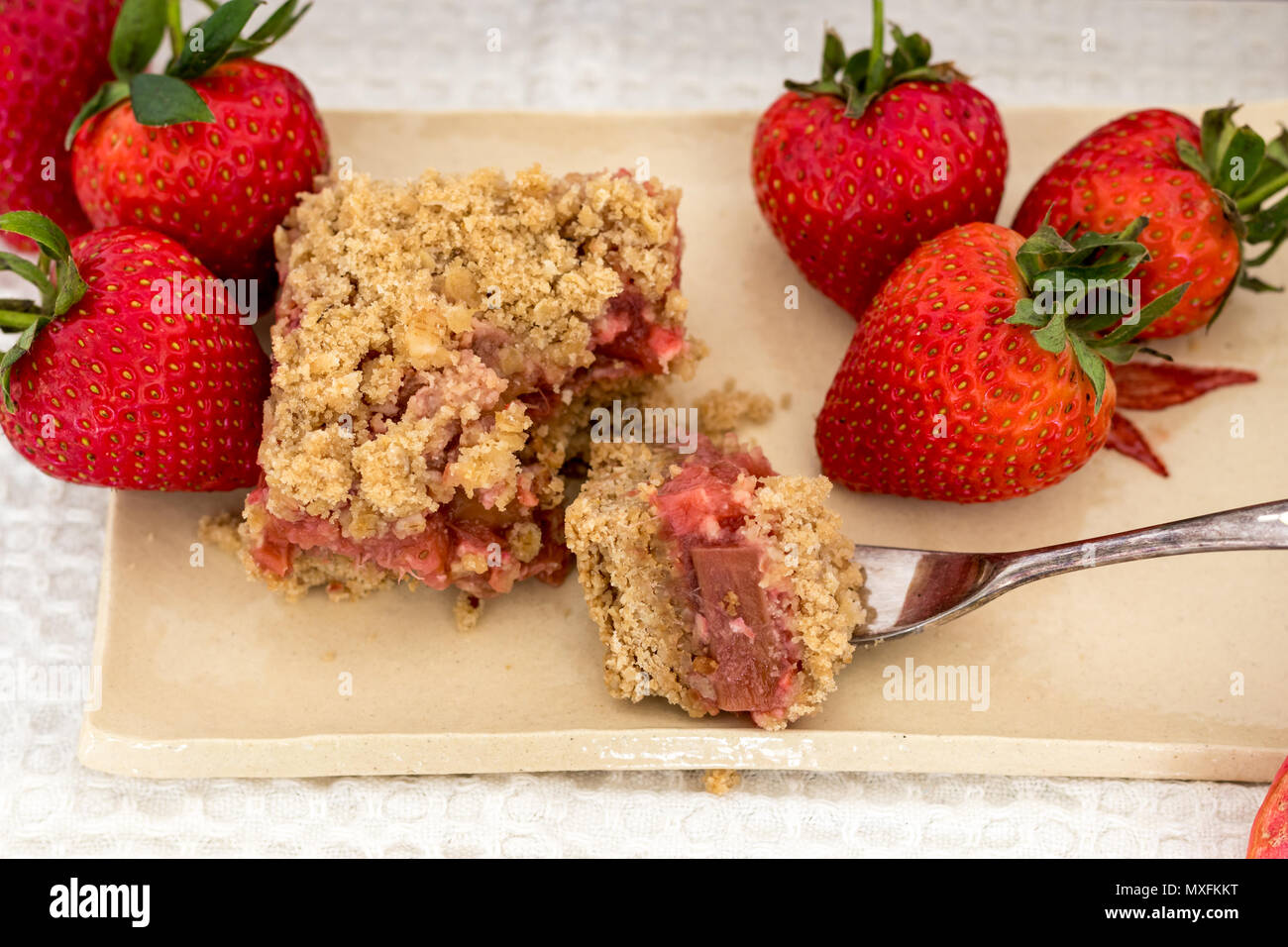 Fette di sani di rosso frutta estiva bar servita su un handmade piastra ceramica. Un delizioso pane appena sfornato dolci con fragole e rabarbaro. Foto Stock