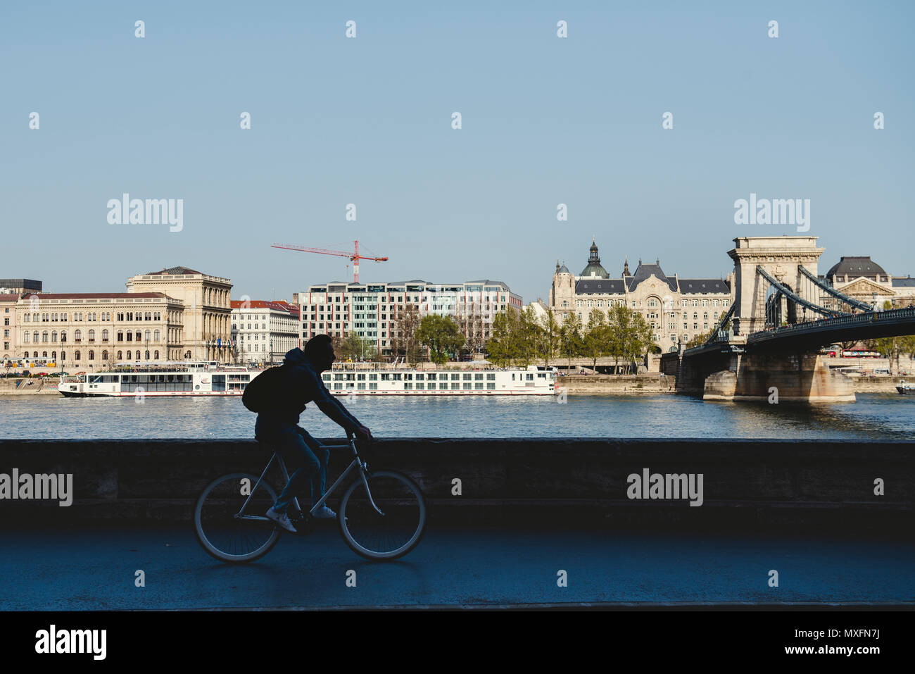 Ciclista silhouette di fronte al fiume Danubio e la catena di Széchenyi Bridge. Foto urbano. Foto Stock