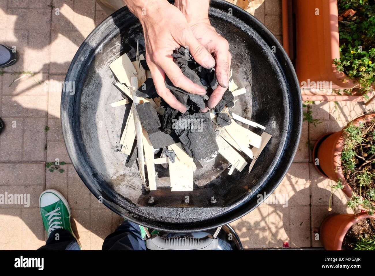 Una giornata di sole in giardino, iniziando il fuoco nel grill e poi cuocere carne con gli amici Foto Stock