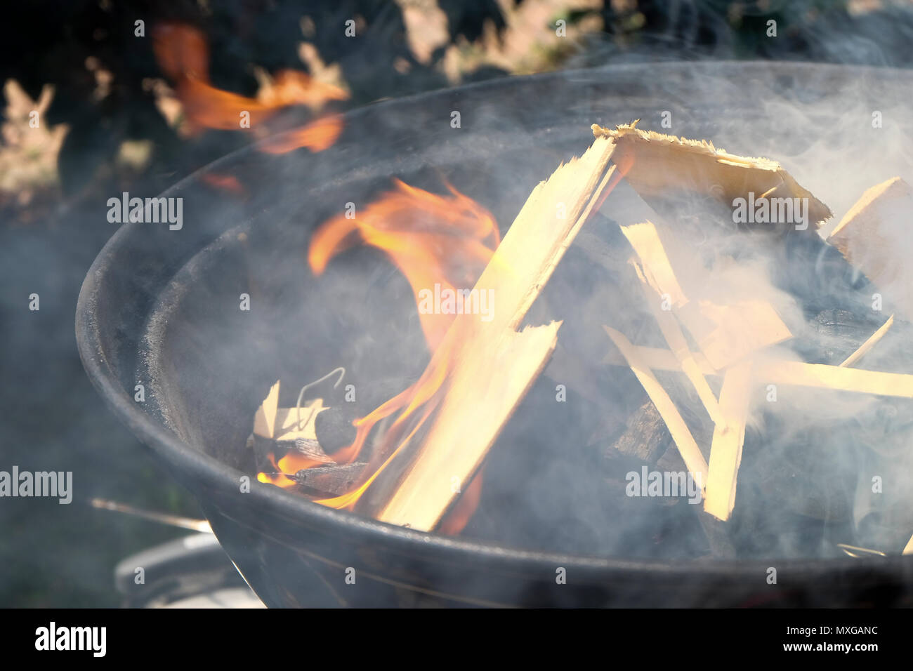 Una giornata di sole in giardino, iniziando il fuoco nel grill e poi cuocere carne con gli amici Foto Stock